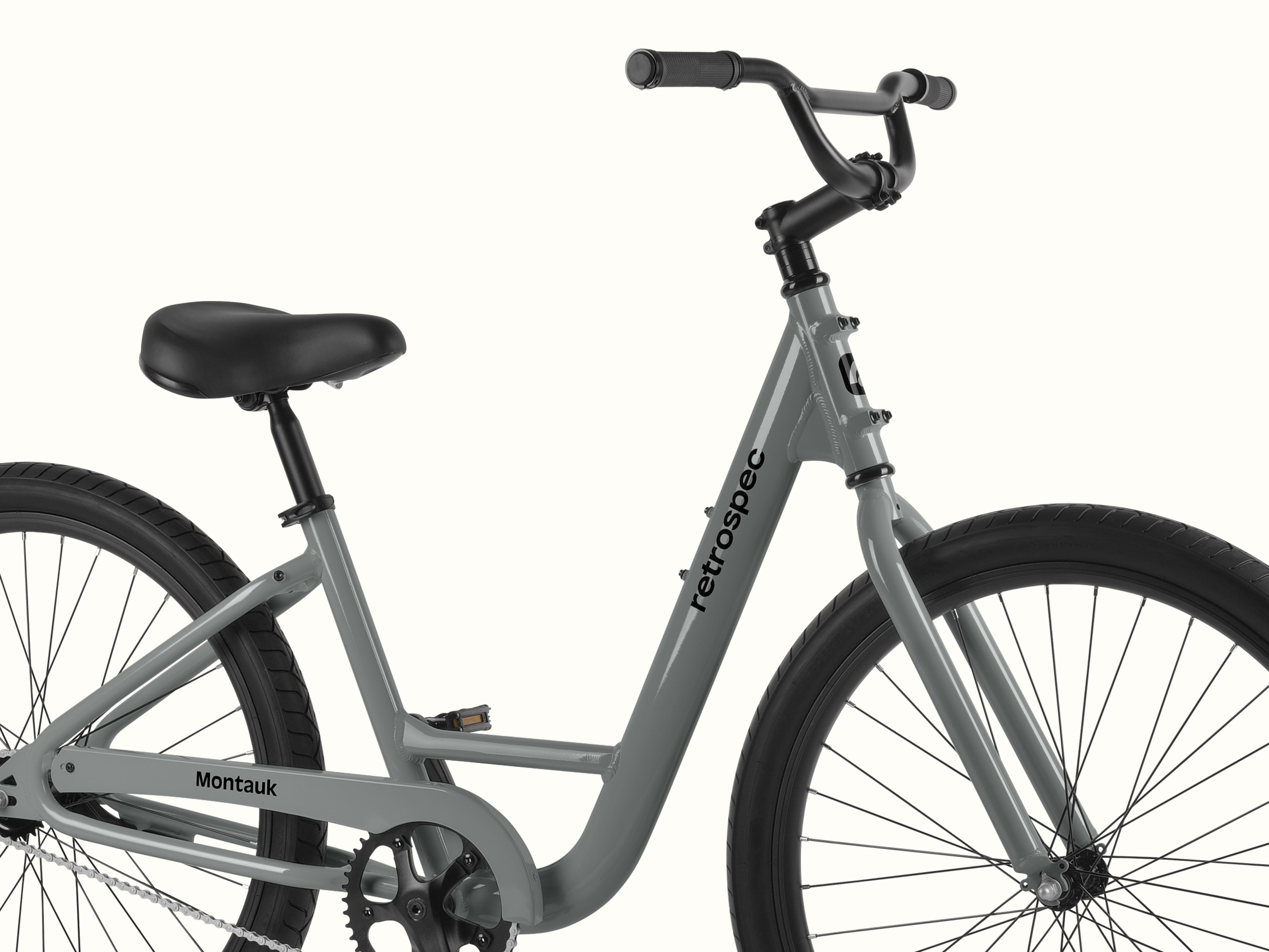 retrospec Montauk 26 comfort bike in Graphite, close-up of the cushioned saddle, swept-back black handlebar, and upright riding position against a clean background.