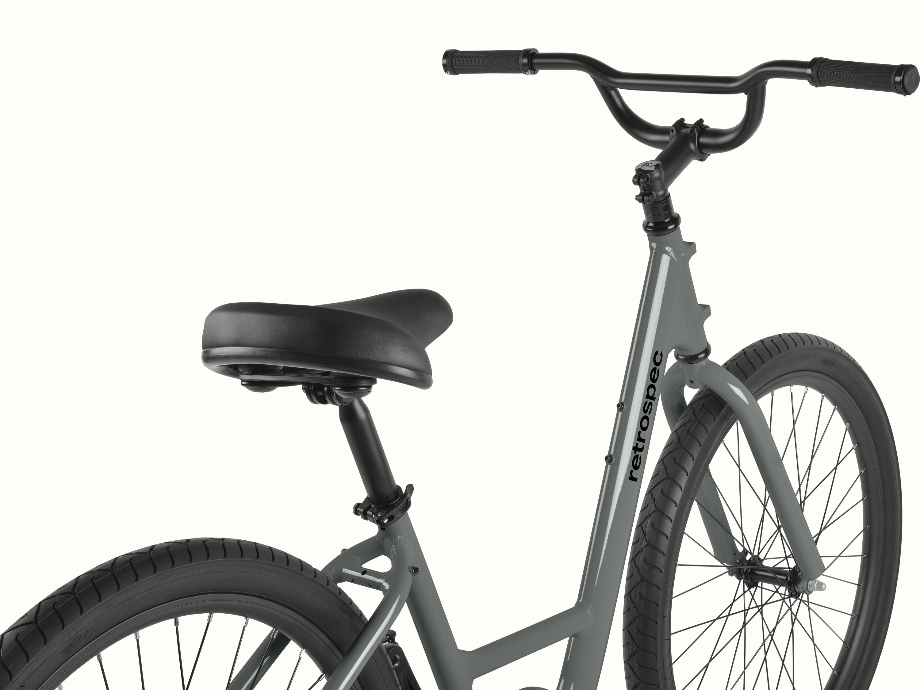 Close-up of the Montauk step through's cushioned black saddle and adjustable seat post, with a quick-release clamp for easy height adjustment and the retrospec down tube logo visible in the background.