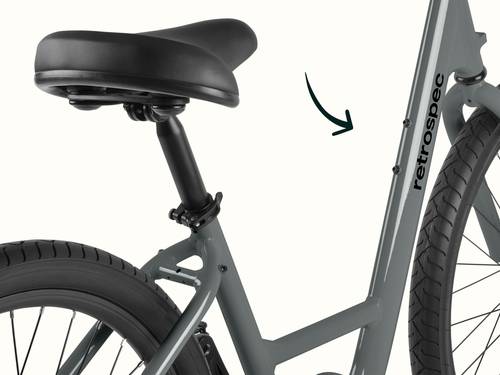 Close-up of the Montauk 7 Speed step through's cushioned black saddle and adjustable seat post, with a quick-release clamp for easy height adjustment and the retrospec down tube logo visible in the background.