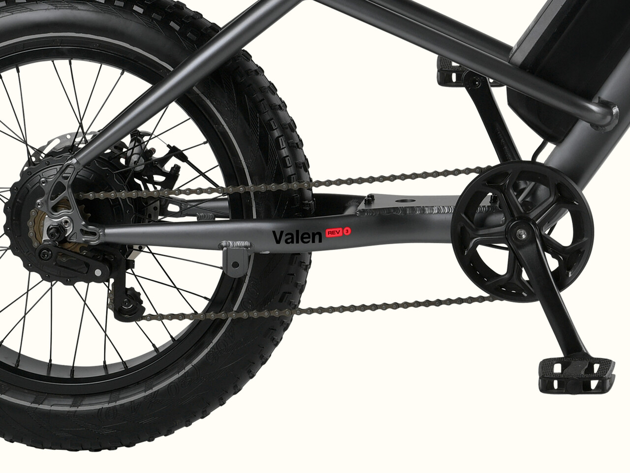 Close-up of a bicycle's drivetrain, featuring a dark frame, chain, and large fat tire, labeled 