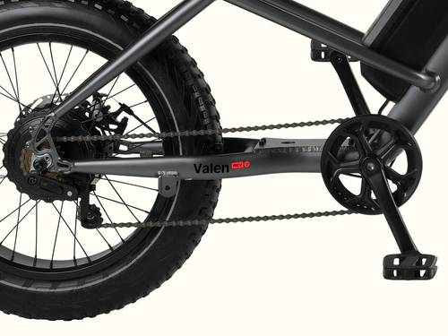 Close-up of a bicycle's drivetrain, featuring a dark frame, chain, and large fat tire, labeled "Valen REV."