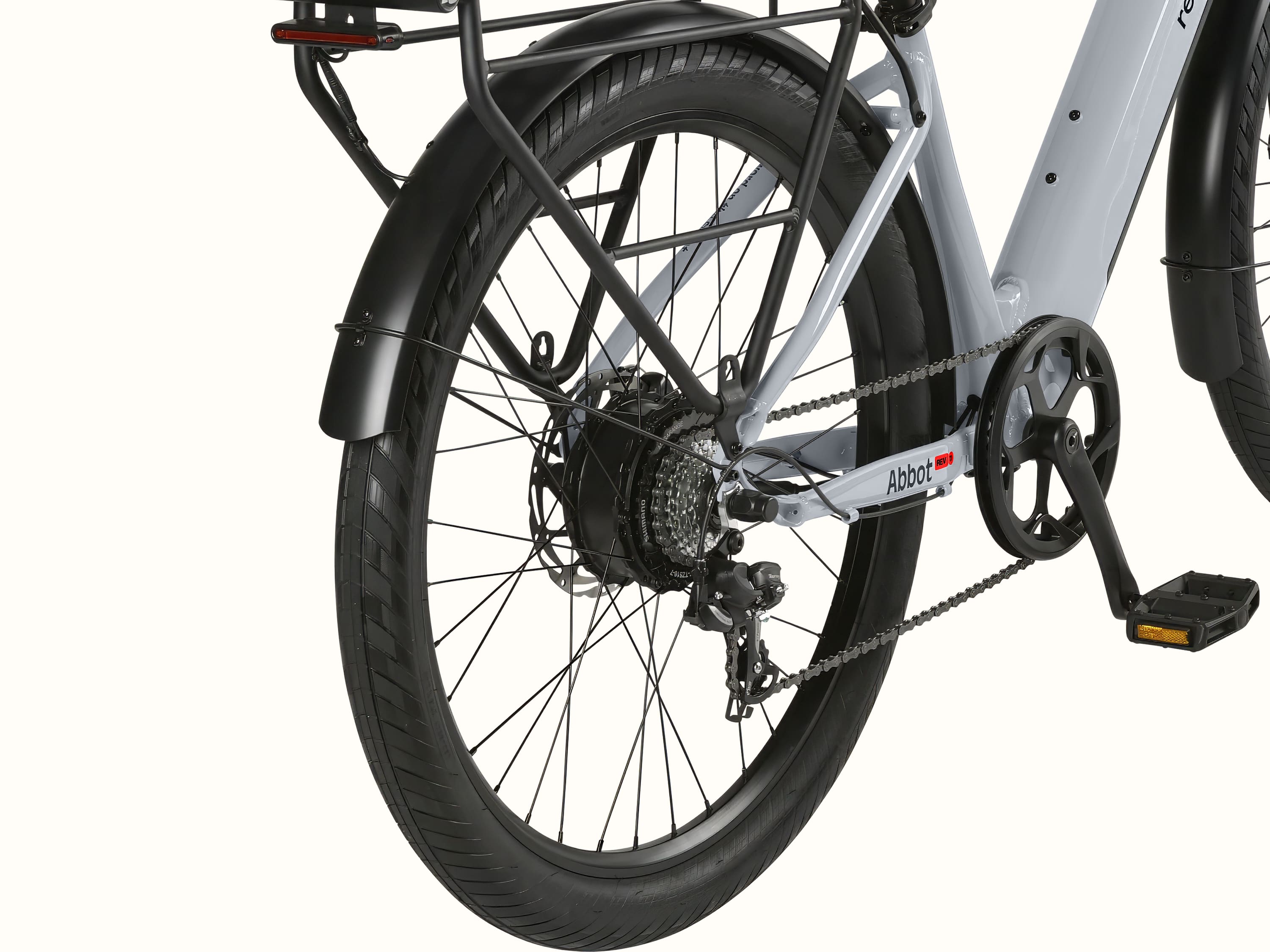 A close up the rear wheel of the gray Abbot Rev 2 EBike with a black fender and rear rack with integrated taillight.