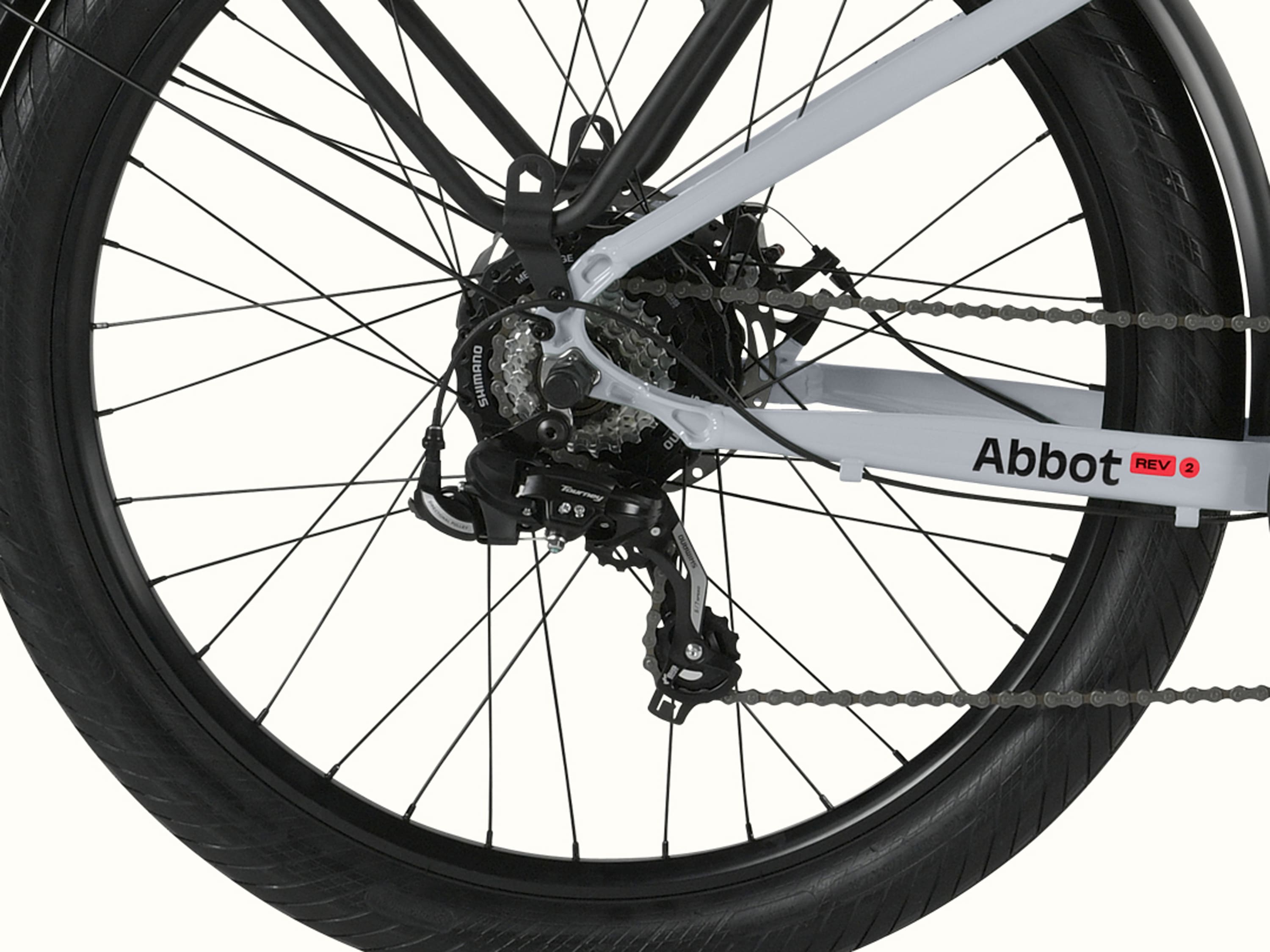A close-up of the rear wheel of the Abbot Rev 2 EBike showcasing the Shimano 7-Speed Drivetrain with Abbot Rev logo.