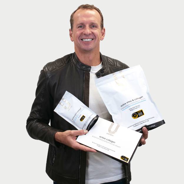 U Perform co-founder Professor Greg Whyte OBE holding a bundle of U Perform sports collagen products Active Collagen, Active Sport Collagen, and Active Whey & Collagen