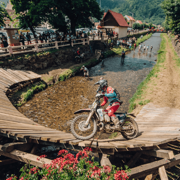 Vanessa Ruck aka @thegirlonabike riding a motorcyle on a wooden bridge over a river