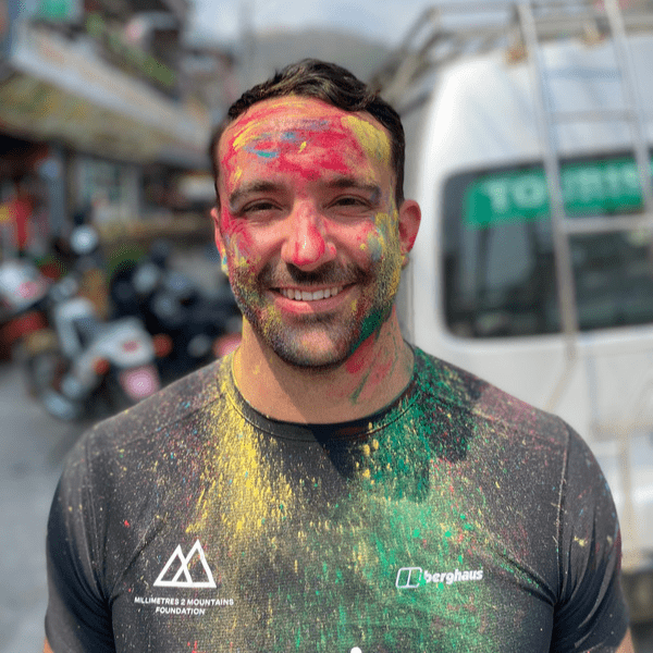 Qigong instructor Arron Collins-Thomas standing covered in paint dust after a colour run event