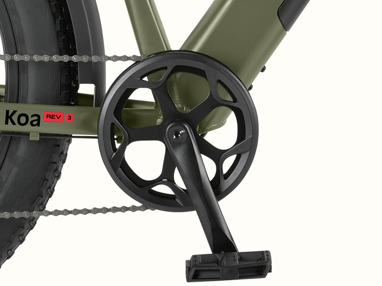 Close-up of the Koa Rev 3 Fat Tire Electric Bike's pedal and crankset, featuring a black circular chainring and robust tires, with 