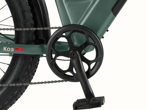 Close-up of the Koa Rev 3 Fat Tire Electric Bike's pedal and crankset, featuring a black circular chainring and robust tires, with "Koa REV 3" branding visible.