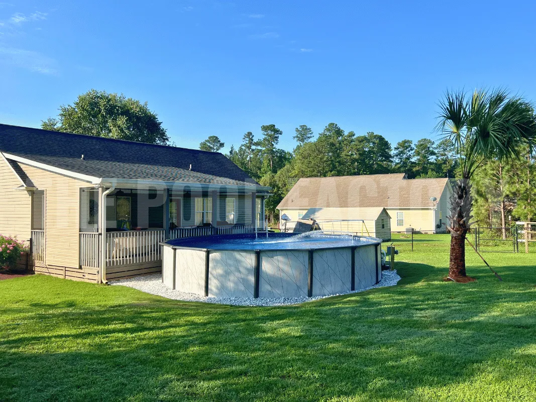 Del Rey above ground round swimming pool with green grass and palm trees surrounding pool. 