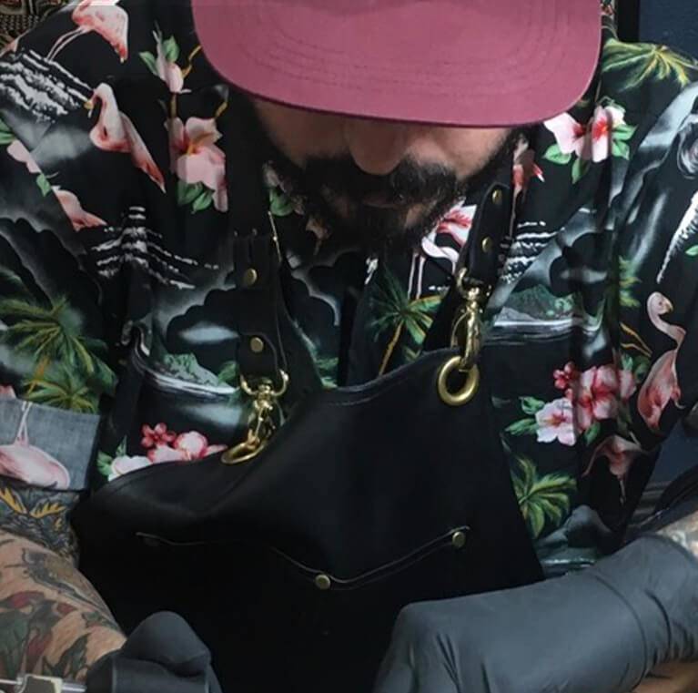 Man in floral shirt and apron working intently.