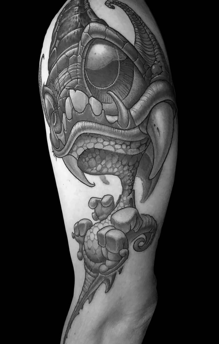 Tattoo of a detailed, horned creature with large eye and claws.