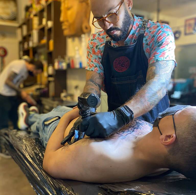 Tattoo artist working on a client's chest piece.