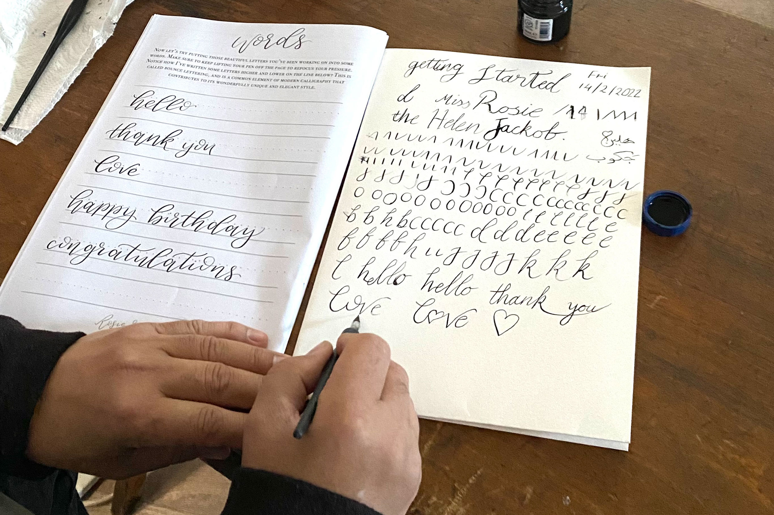 An image of hands practicing calligraphy in a sketchbook 