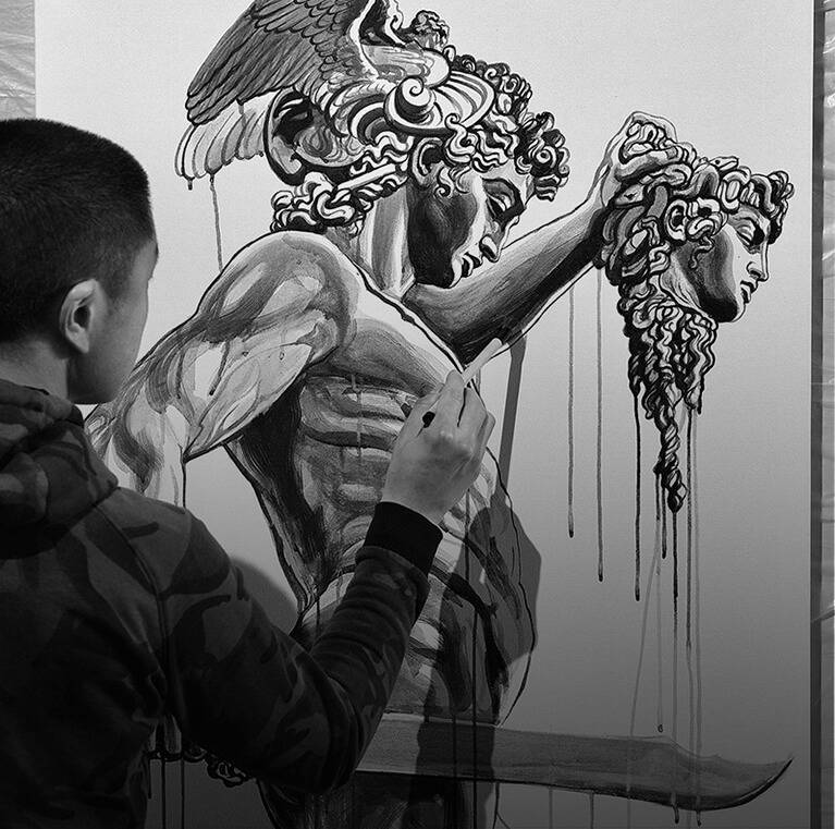A person is painting a dramatic black and white depiction of a mythical warrior holding a severed head.