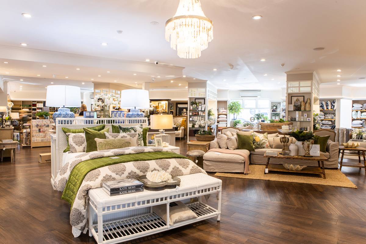 A stunning bed with green quilt and white rattan bed stool are beautifully merchandised in this photo of the Alfresco Emporium Bundall store.