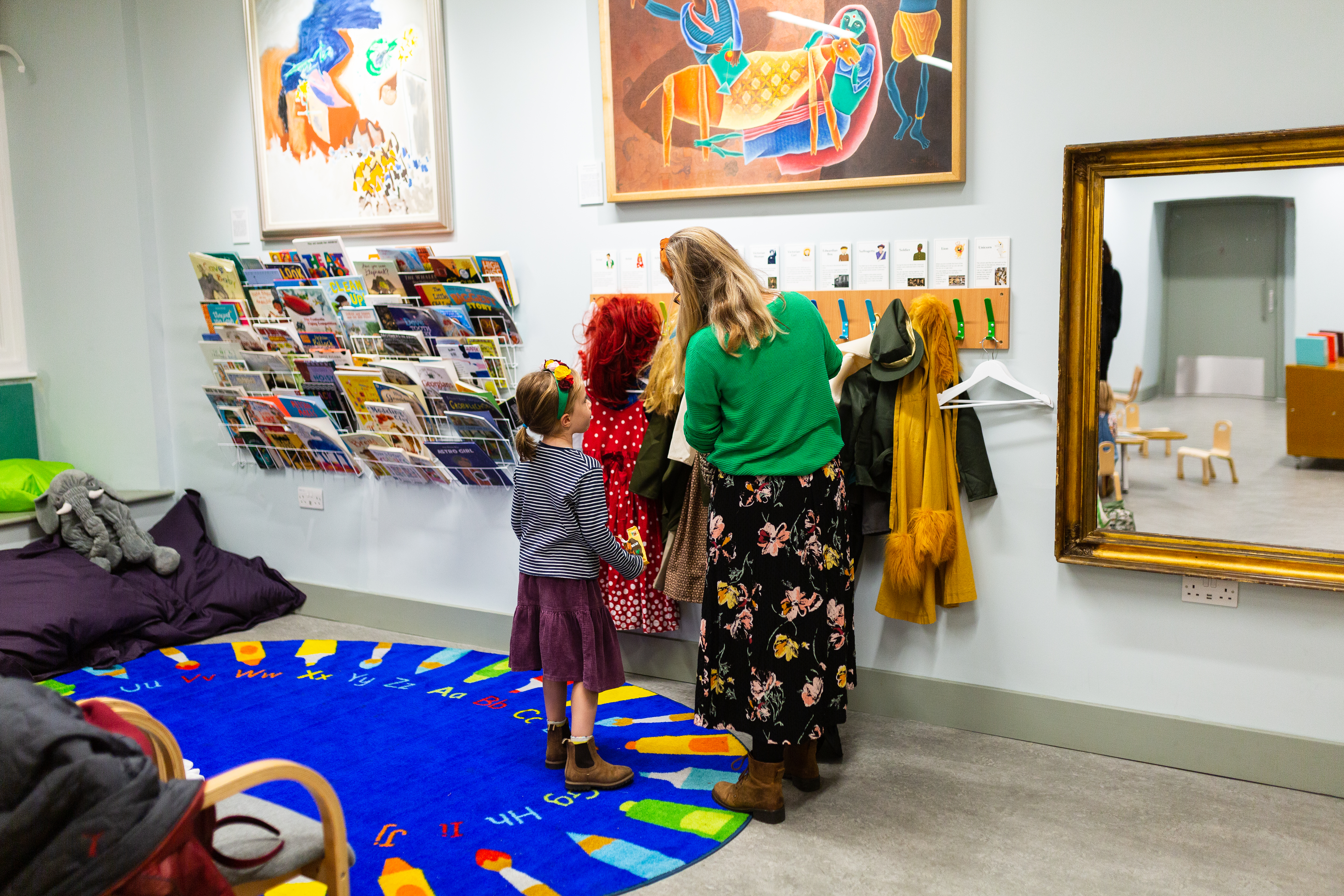 A selection of books, costumes and a mum and child browsing the costumes in the RWA Family Activity Space 