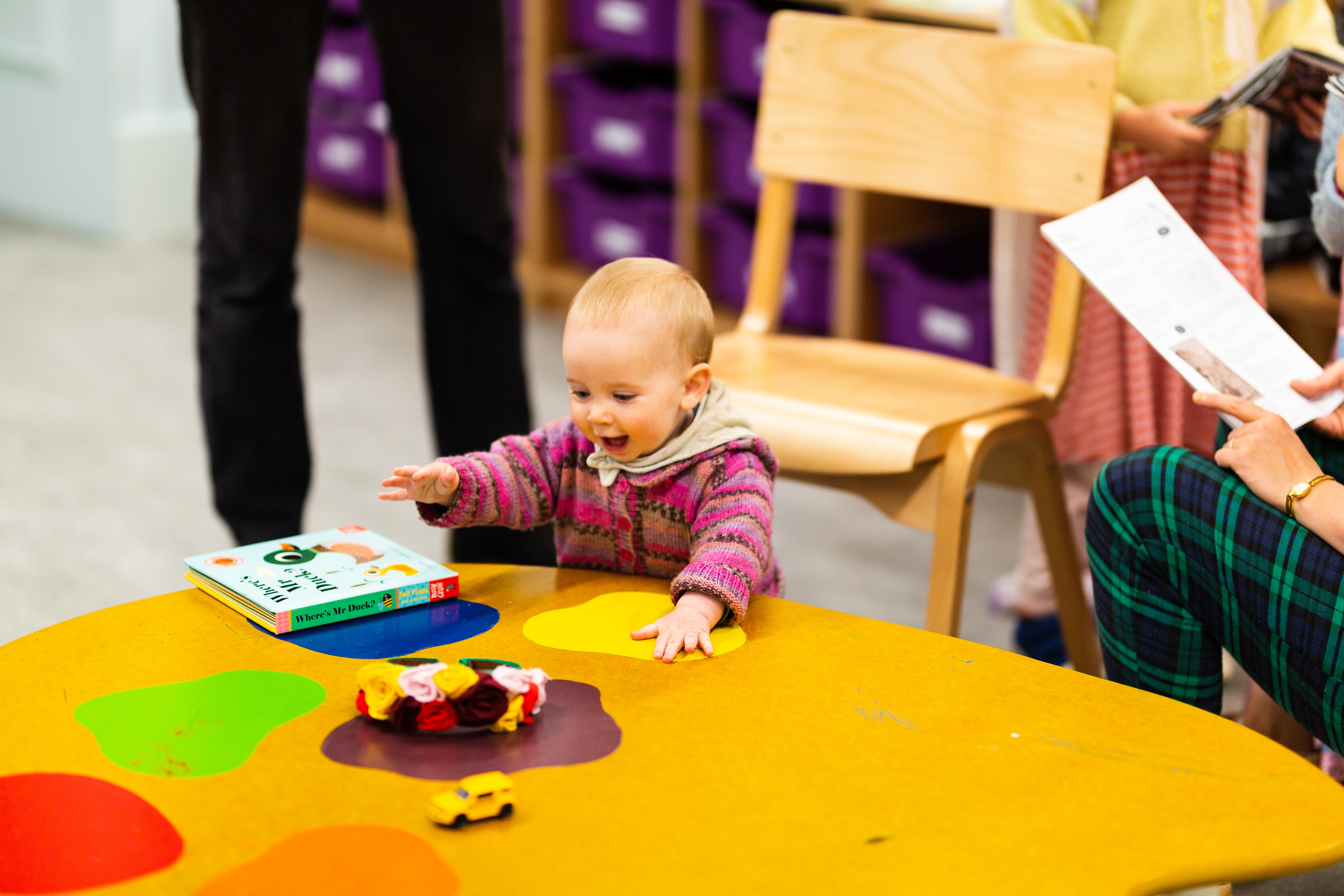 A young toddler, playing at a table painted like a paint palette 