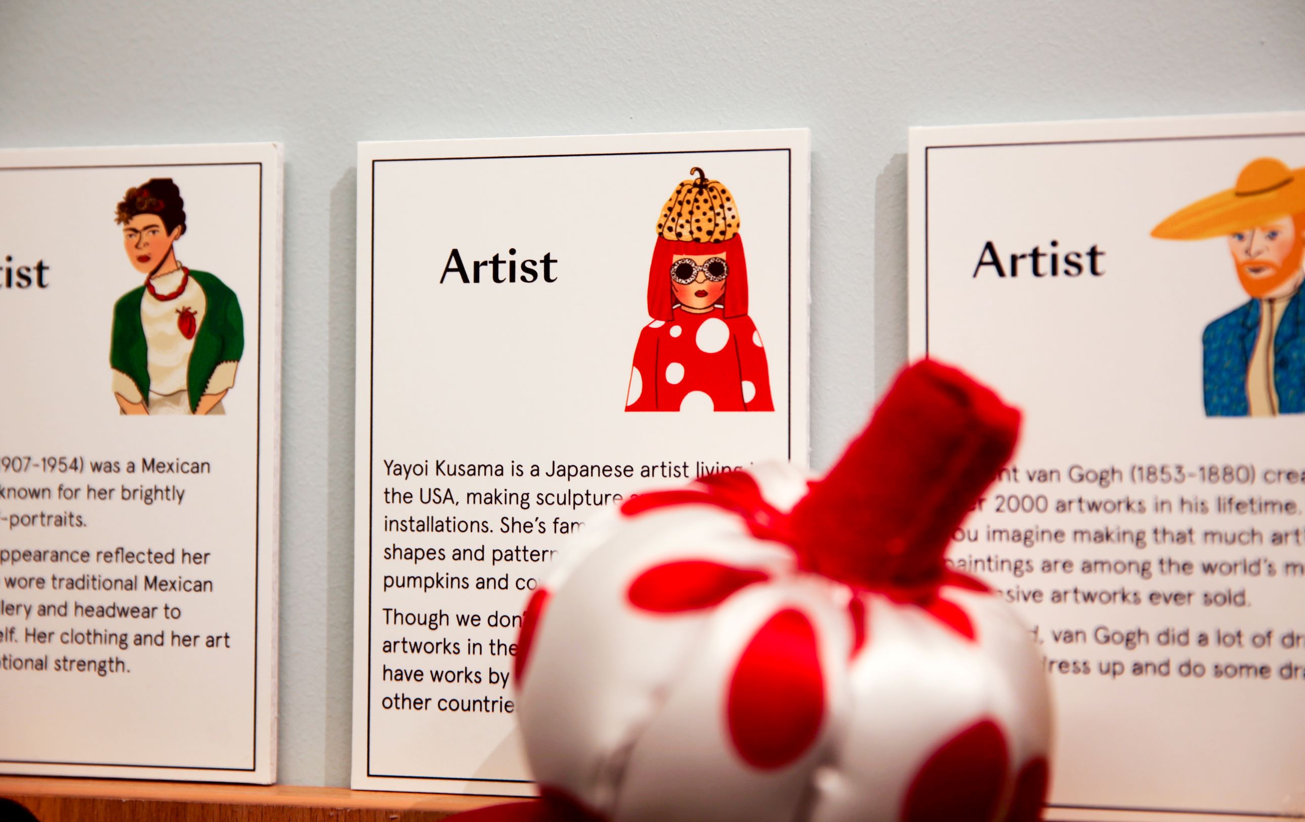 Three wall mounted cards displaying artist profiles in the Family Activity Room 