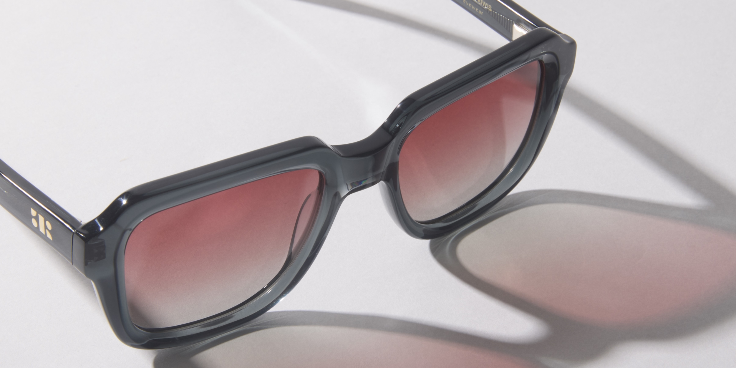 Photo Details of Reuben Sun Clear Burgundy Sun Glasses in a room