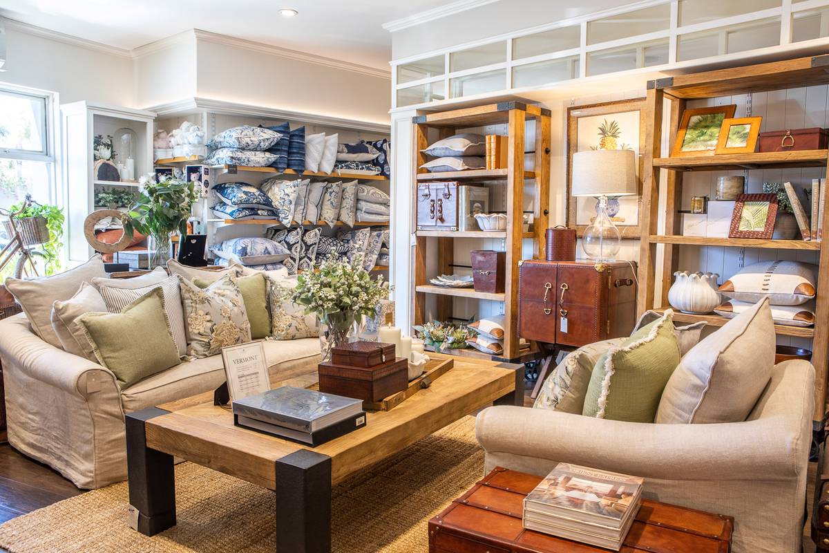 A lounge room beautifully styled with soft green cushions, leather bar, elm coffee table and natural jute rug at the Alfresco Emporium Bundall store.